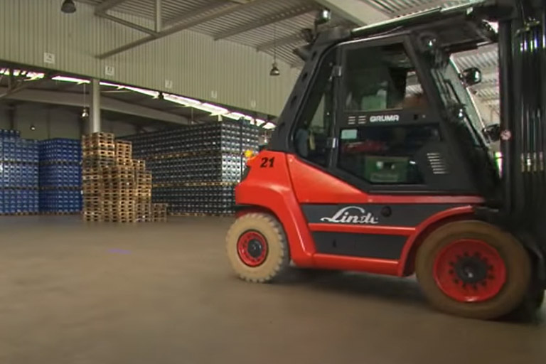 linde forklift red in warehouse drives with many beer crates light, door, pallet