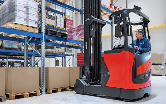 Man stores goods on the shelf with Linde reach truck