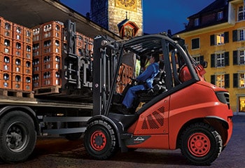 Man with forklift unloads truck with crates of drinks
