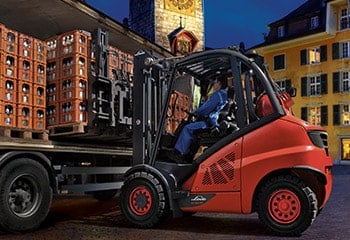 Man with forklift unloads truck with crates of drinks