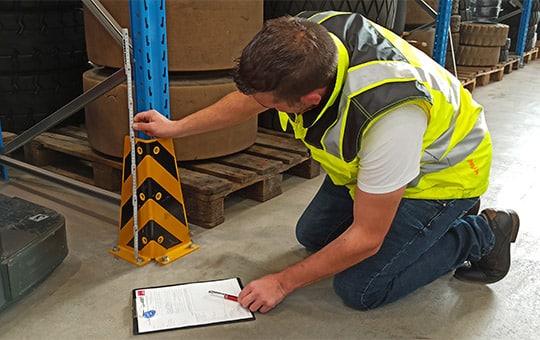 Inspector measures high rack with tires and forklift during rack inspection