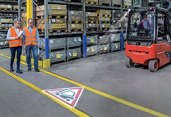 Testing work equipment warehouse persons with high-visibility vest and forklift truck