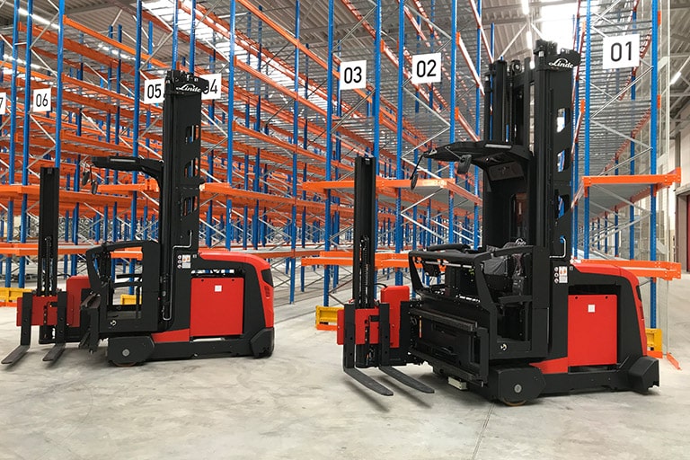 Two Linde narrow aisle trucks in front of high bay racking